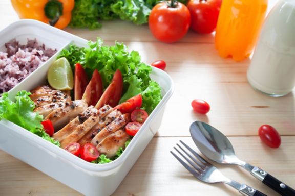 Close up of lunch box, Grilled chicken breast with lettuce, tomatoes, lime and ricr berry. Healthy lifestyle