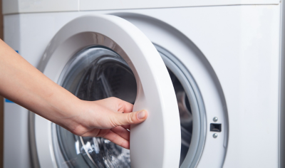Hand opened the door of washing machine.