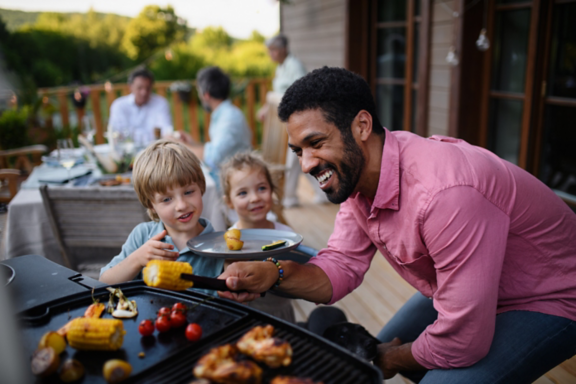 Une famille fait un barbecue sur une terrasse.