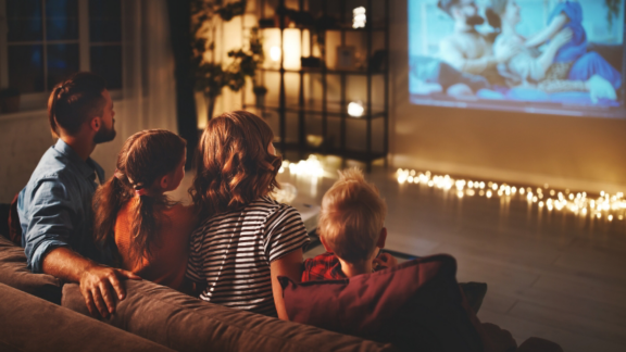Beautiful young couple in love at home, celebrating with a gift box exchange, kissing