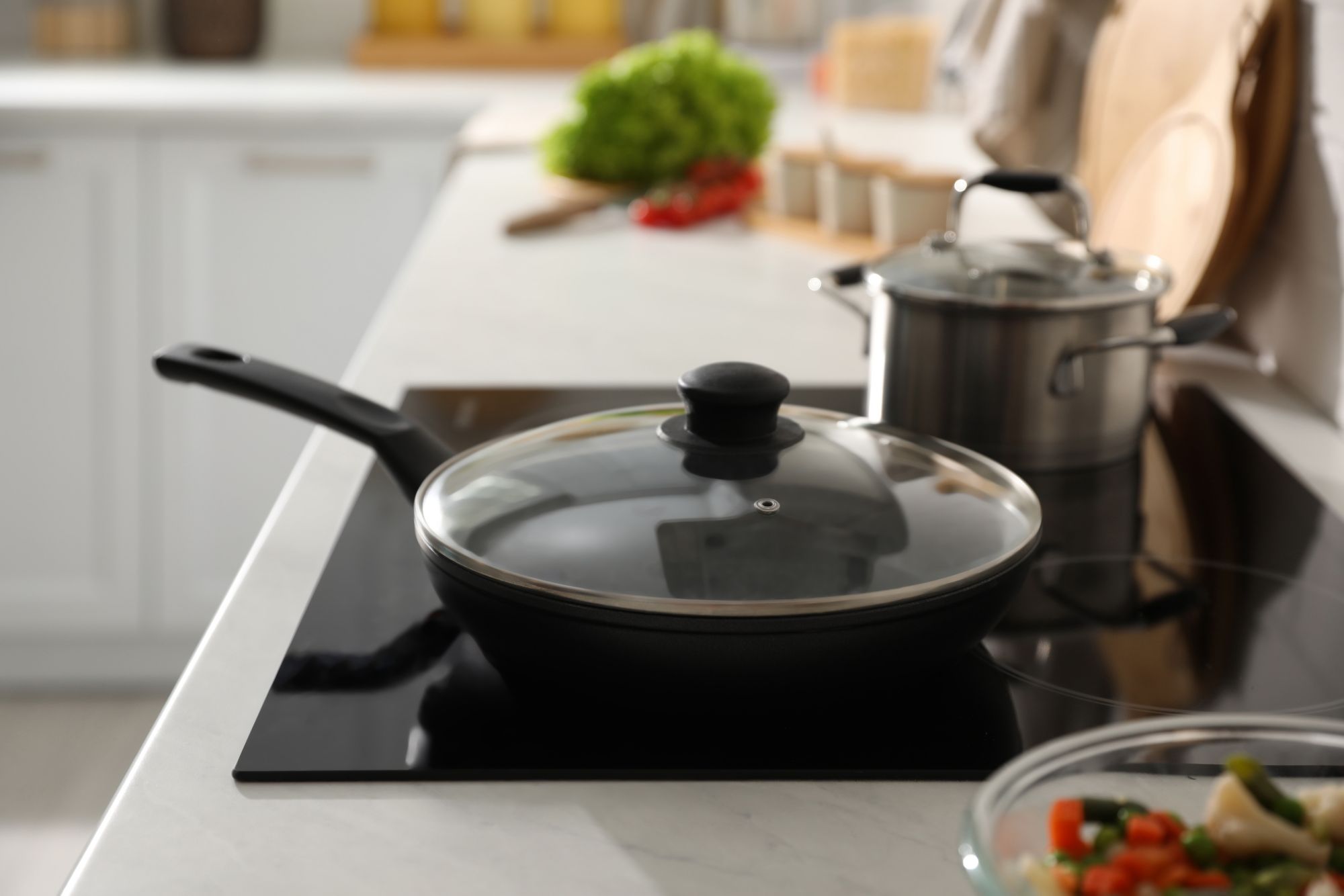Frying pan with lid on cooktop in kitchen