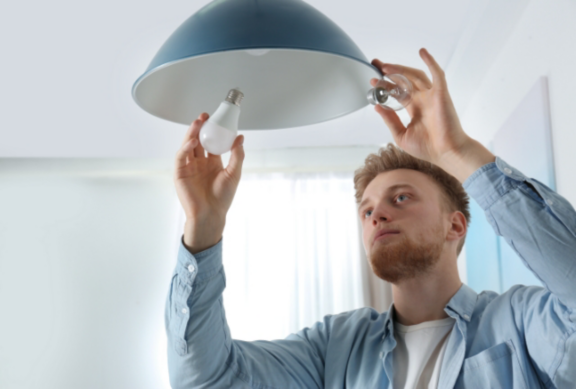 Man changing light bulb in pendant lamp indoors