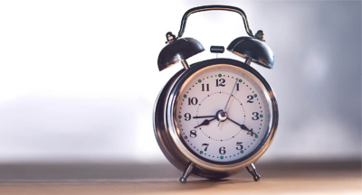 Retro alarm clock on table. Vintage style sepia photo